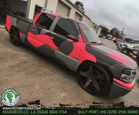 Custom vehicle wrap with bold red and black design for trucks.