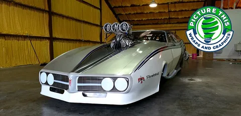 Custom wrapped vintage drag racing car with bold graphics and racing decals.