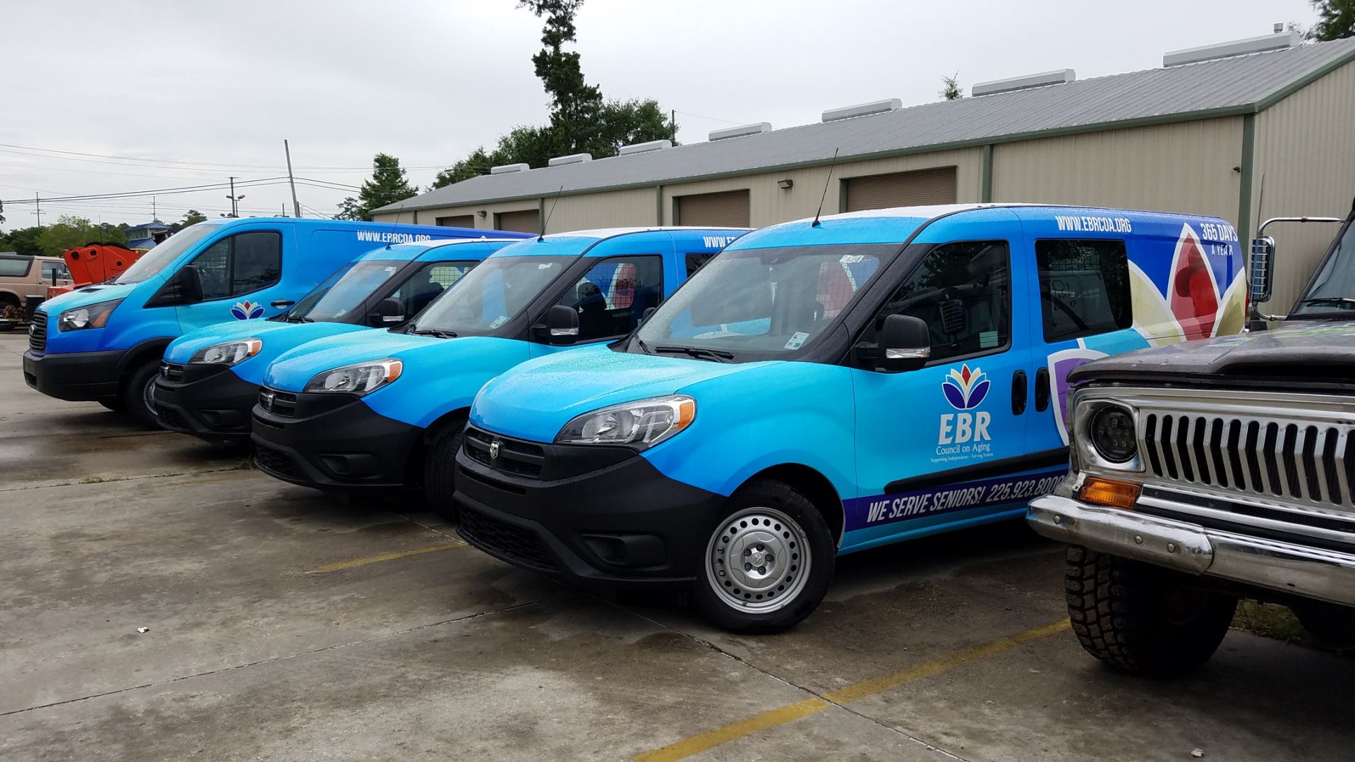 Company fleet of blue vans and trucks with matching commercial wraps